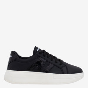 Tenis de mujer negros con cordones y suela blanca gruesa.