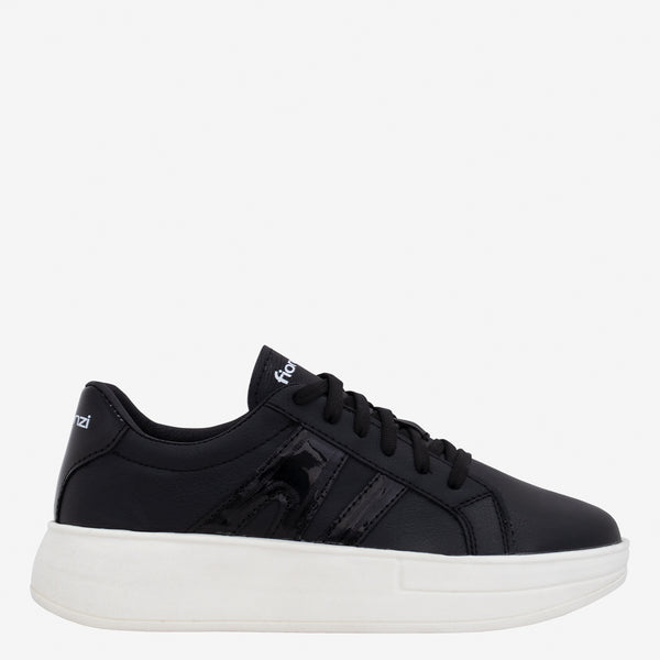 Tenis de mujer negros con cordones y suela blanca gruesa.